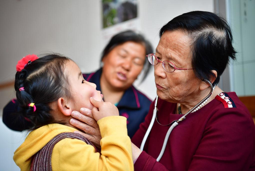 2018年4月29日,路生梅(右一)在家中給一名小朋友看病。新華社記者 邵瑞 攝